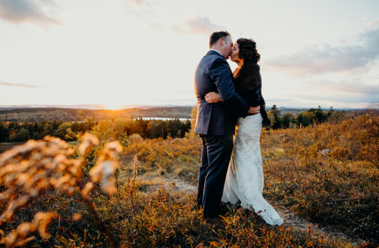 A couple kiss during sunset at their Acadia National Park elopement ceremony