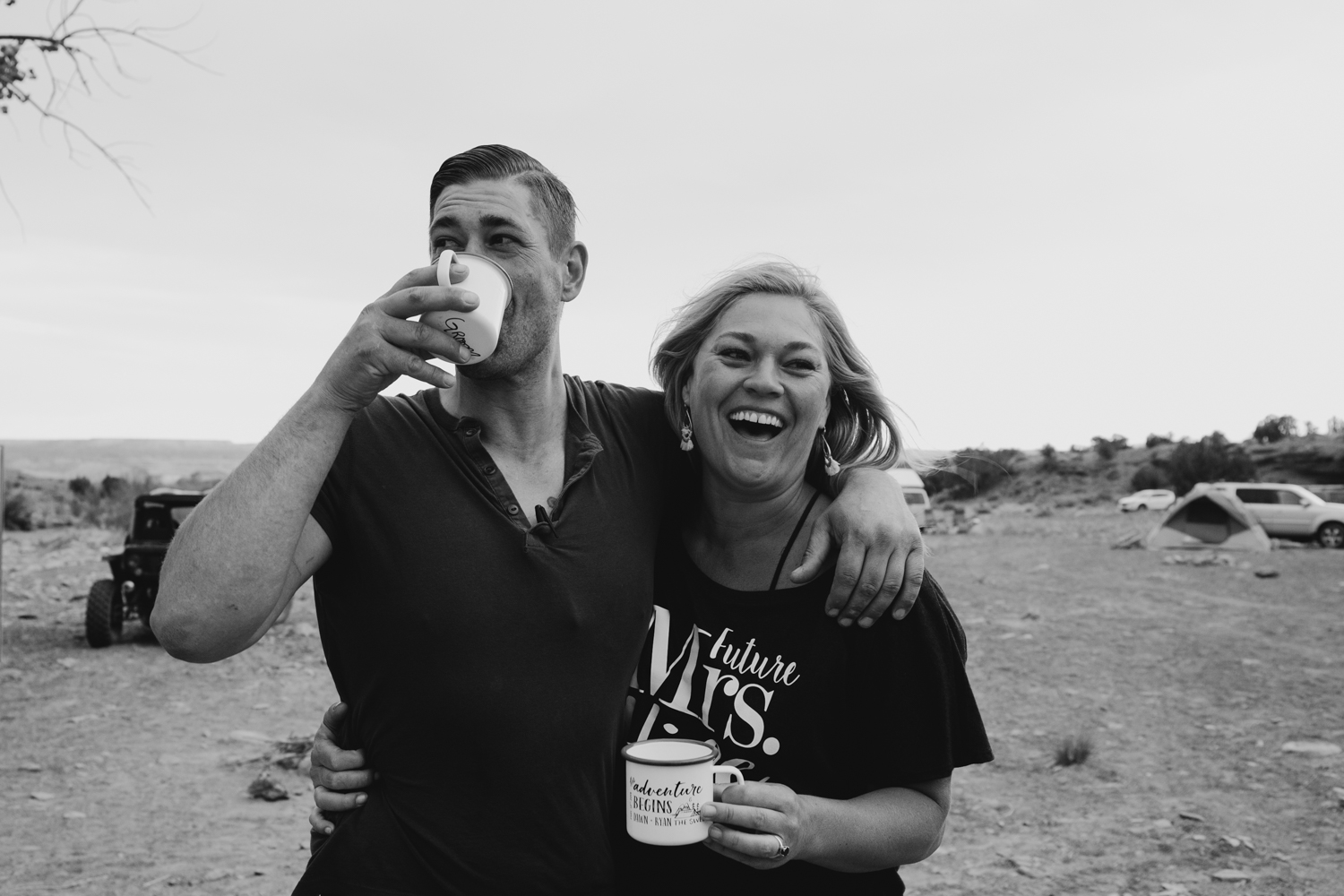 Couple laugh and embrace while drinking coffee before their backcountry utah wedding