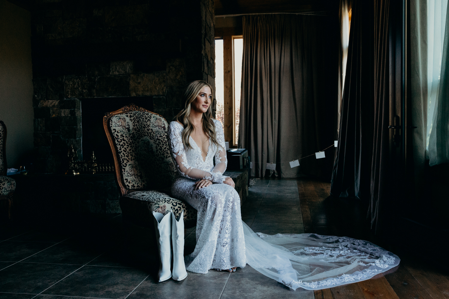 Bride sits in ranch house with white cowgirl boots as she gets ready for her intimate Jackson Hole wedding