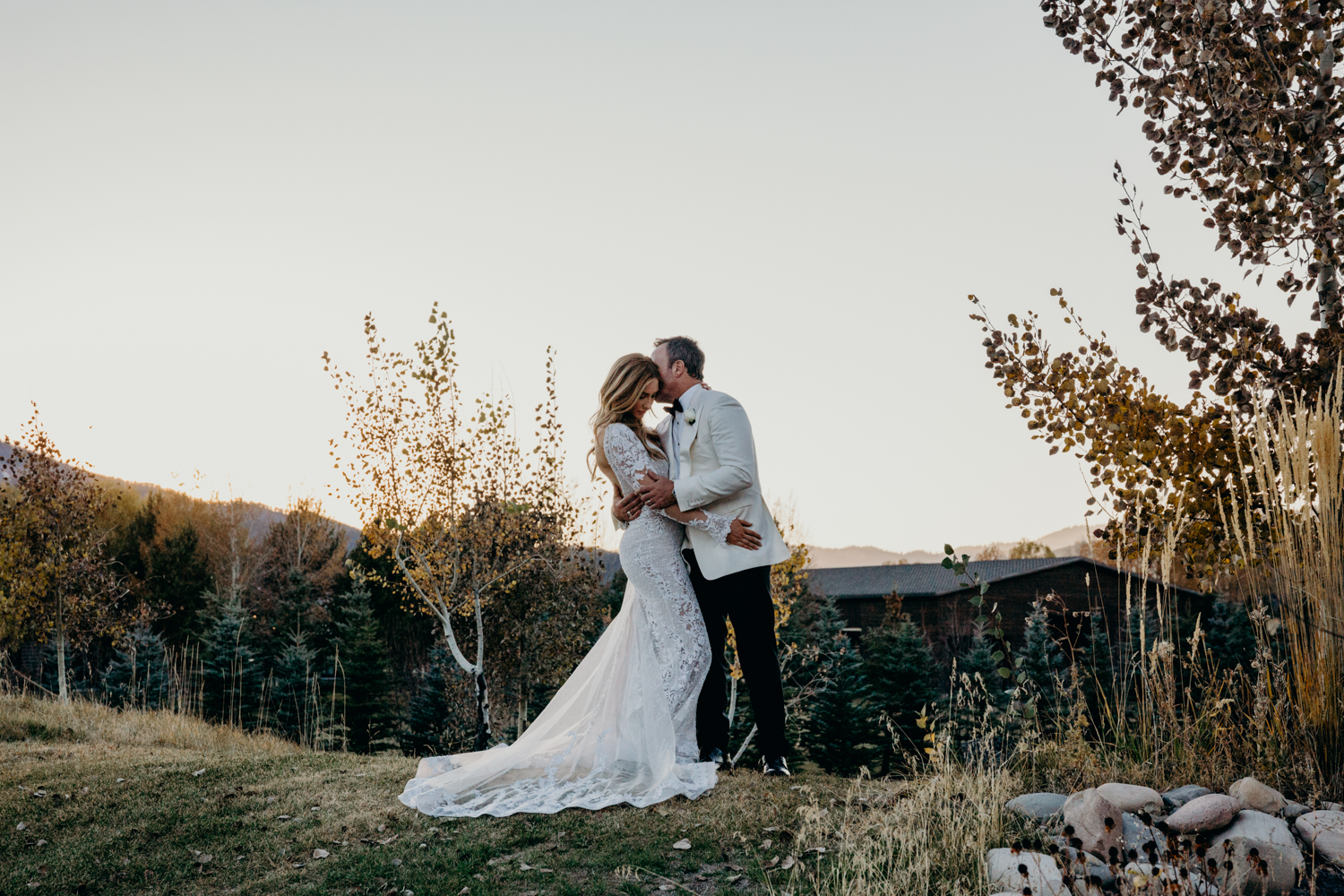 Couple embrace on a hillside during sunset at their Jackson Hole wedding
