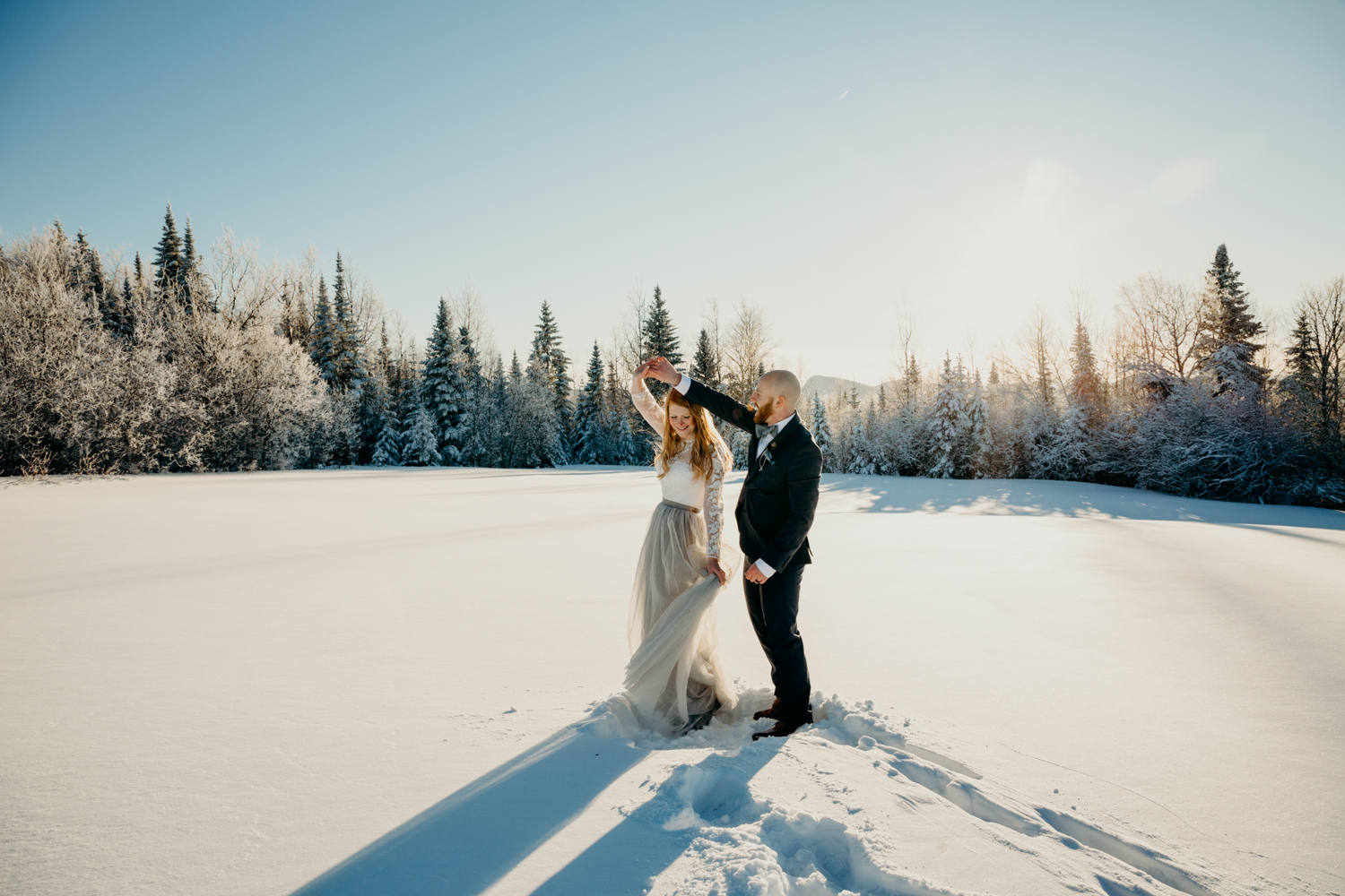 Man and woman dance in a snowy field at their winter elopement in Northern Vermont